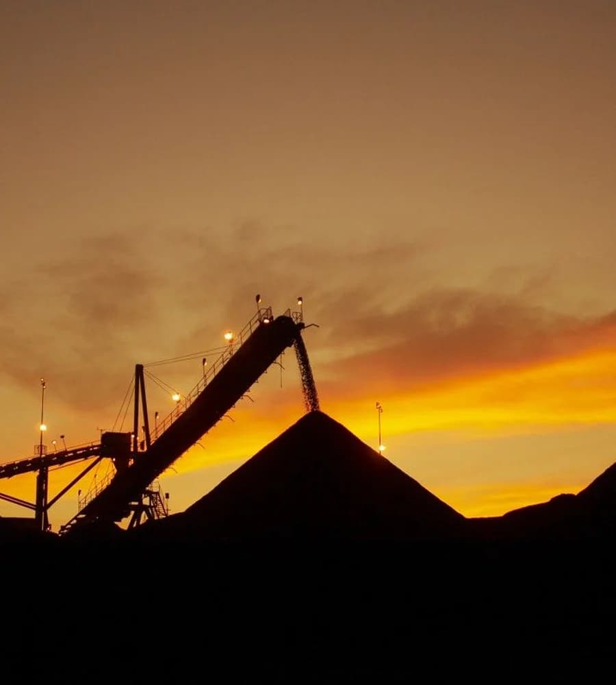 A coal stockpile and conveyor silhouetted at dusk on an Australian mine